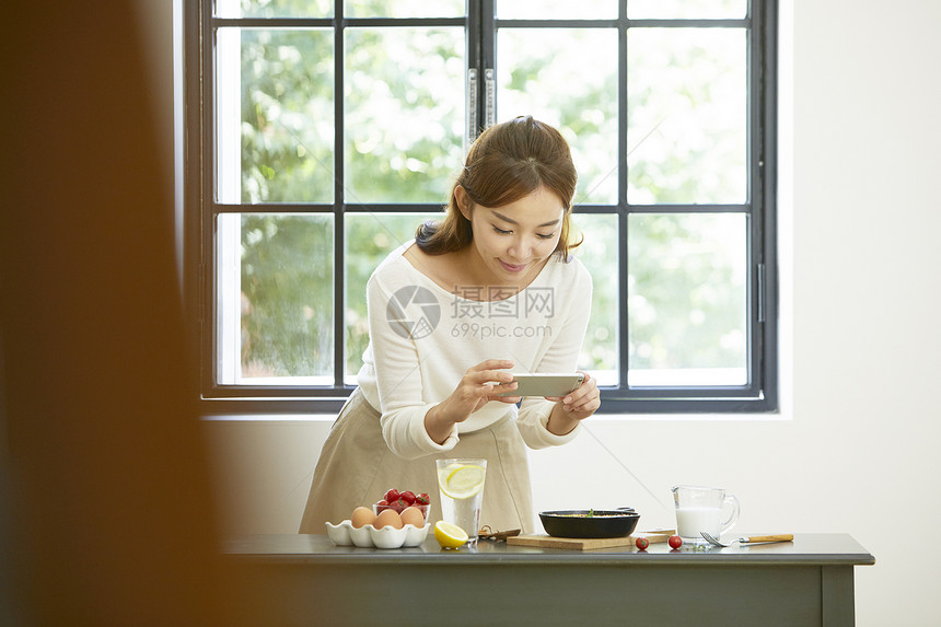 女青年拿着手机拍照食物图片图片