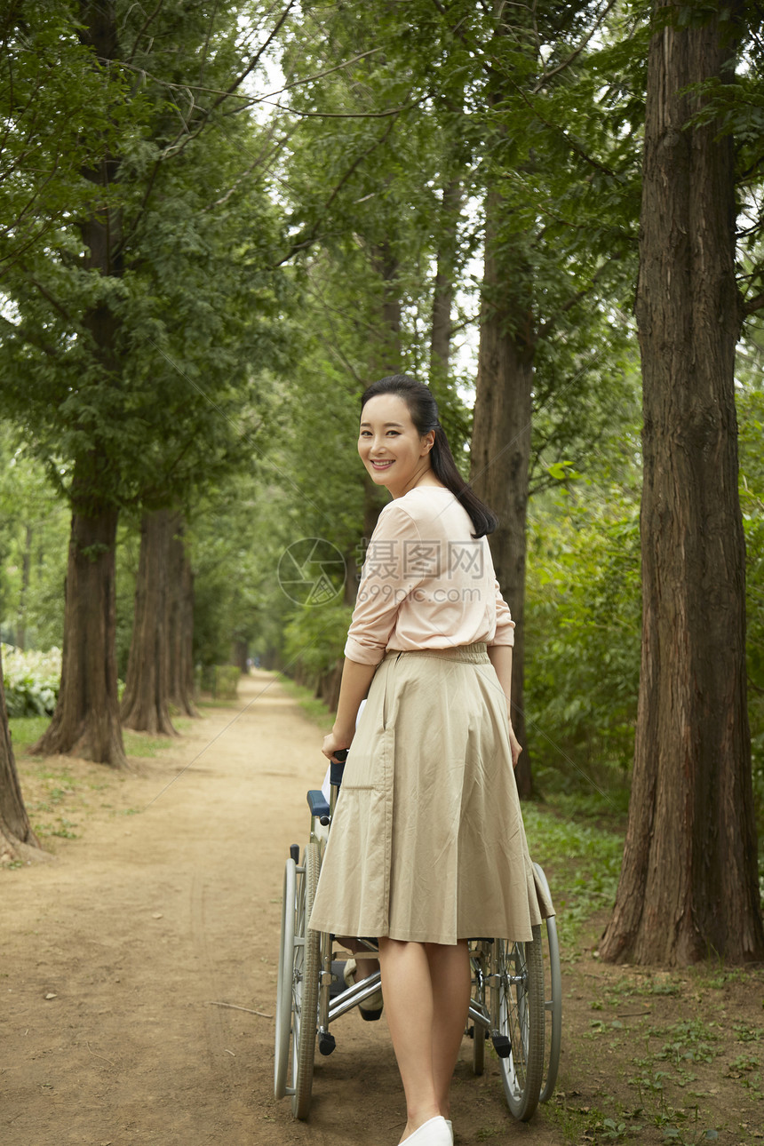 女儿推着轮椅走在树林里图片