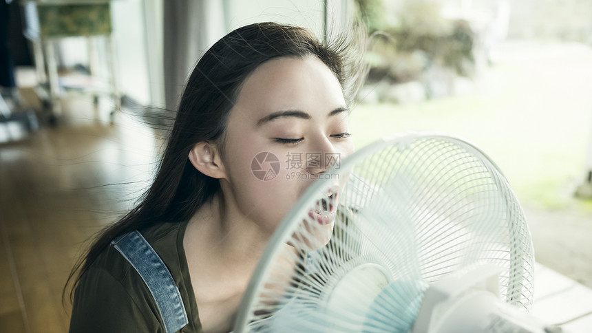 在房间里吹电风扇解暑的女孩图片