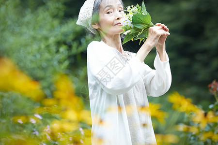 庭院里闻着花束的老年女性图片