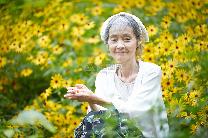 老年妇女在庭院花海里图片