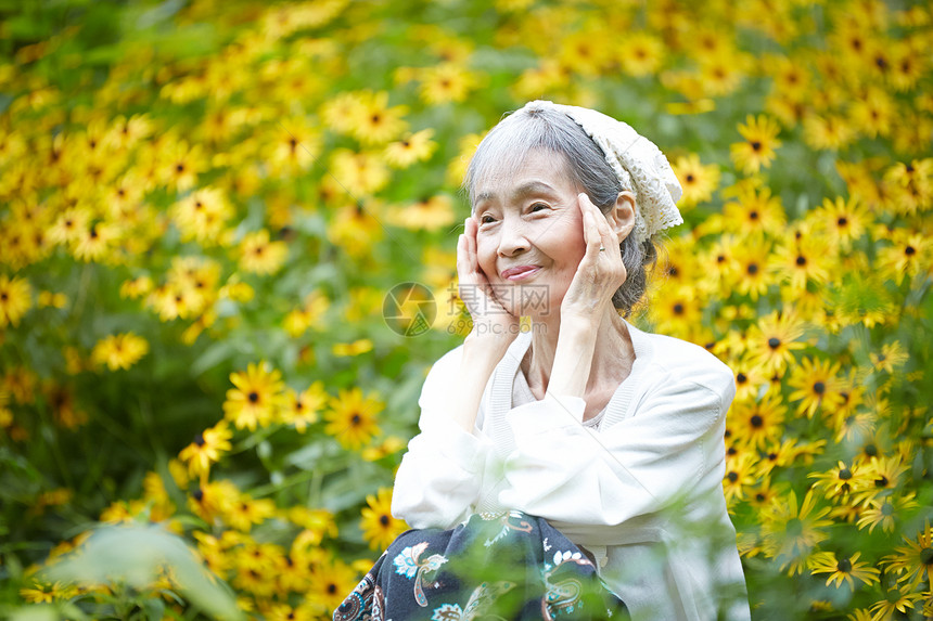 院子植物的自然放松的老年妇女图片