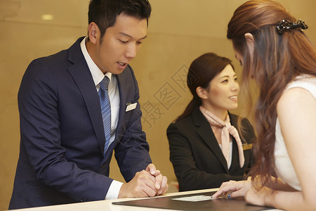 微笑信息占有在酒店接待处工作的男人和女人商务人士高清图片素材