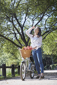 公园郊游里推着自行车的女青年图片