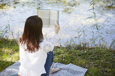 河岸边阅读的女性背影图片