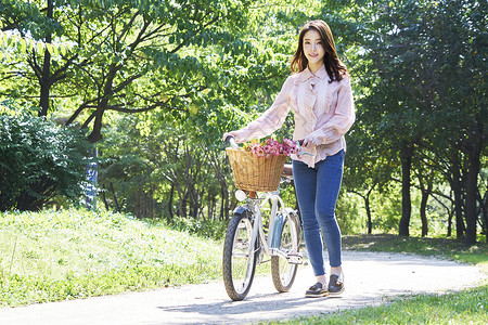 年轻女子公园里推着自行车行走图片