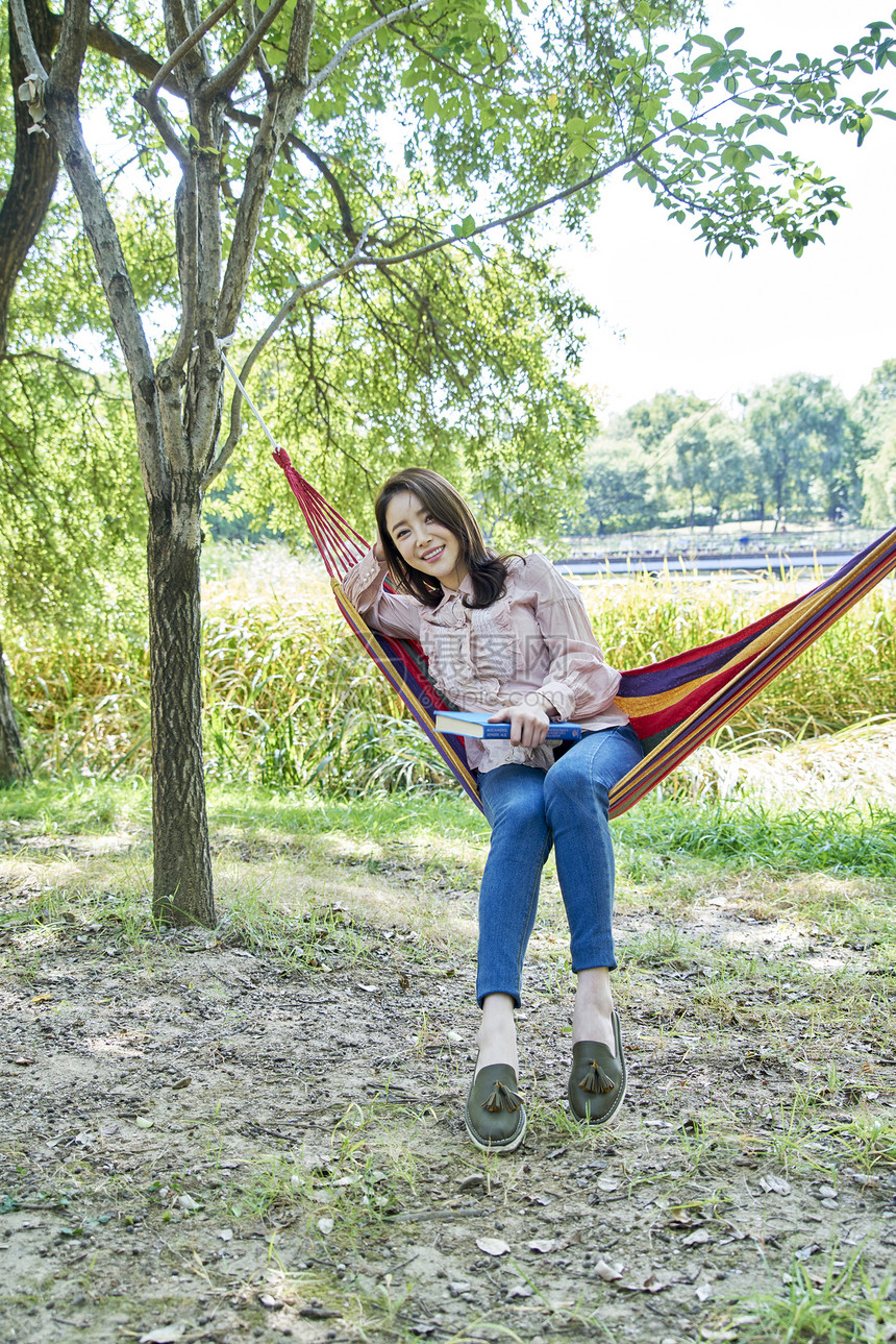 坐在公园吊床上休息的青年女性图片