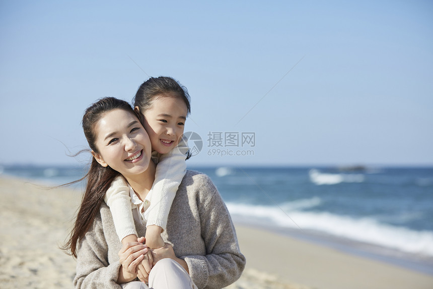 海边沙滩上在妈妈背上的女孩图片
