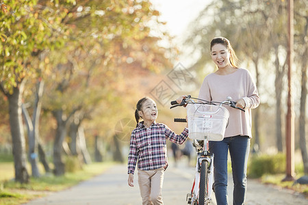母女推行双人自行车游览公园背景图片