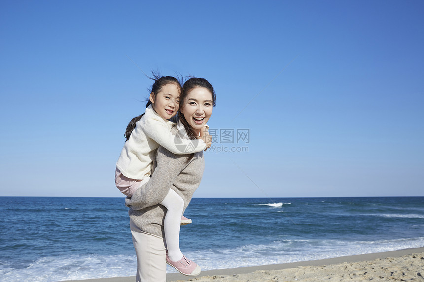 海边沙滩上在妈妈背上的女孩图片