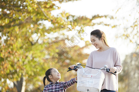 母女推行双人自行车游览公园背景图片