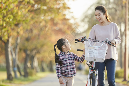 母女推行双人自行车游览公园背景图片