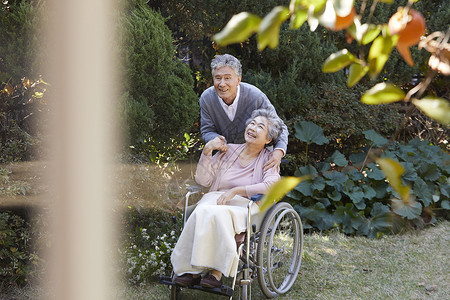 爷爷照顾坐轮椅的奶奶户外的高清图片素材