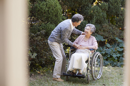 爷爷照顾坐轮椅的奶奶微笑高清图片素材