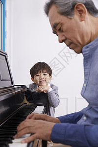 男孩看着爷爷弹奏钢琴幸福高清图片素材