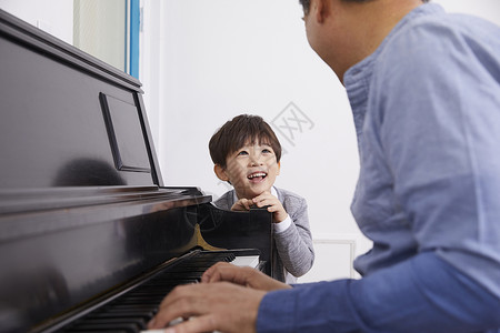 男孩看着爷爷弹奏钢琴60年代高清图片素材