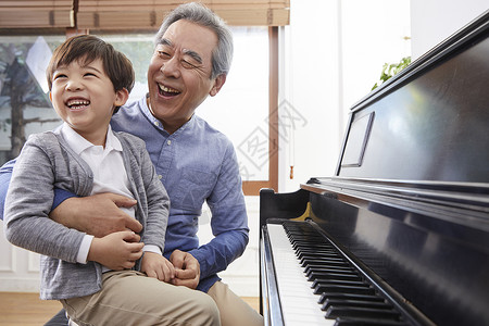 快乐祖父孙子一起弹钢琴熊抱高清图片素材
