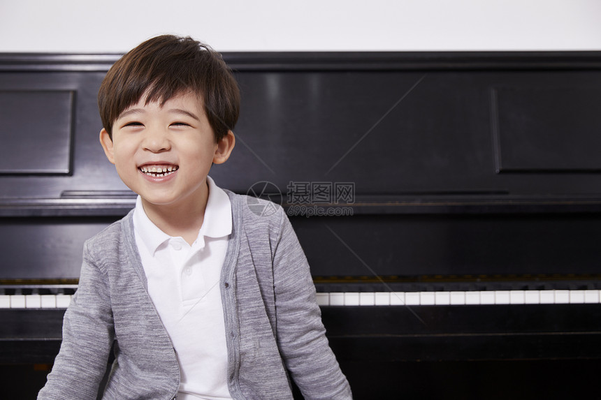 在钢琴前的微笑男孩图片