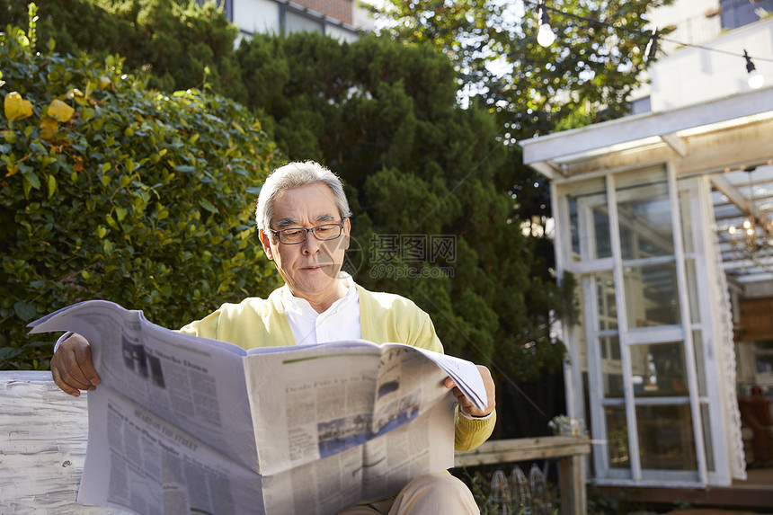老人在室外看报纸图片