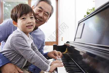 快乐祖父孙子一起弹钢琴家庭高清图片素材