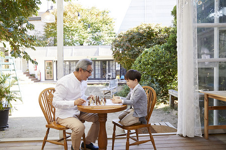 祖父孙子在花园下象棋学习高清图片素材