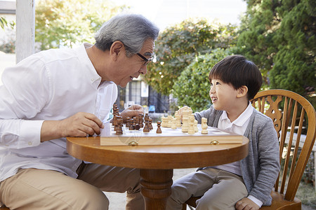 祖父孙子在花园下象棋长辈高清图片素材