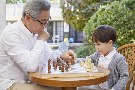 微笑祖父孙子下国际象棋桌子高清图片素材