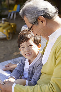 快乐祖父孙子一起在长凳看报纸图片