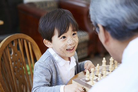 孙子看着爷爷下国际象棋家庭高清图片素材