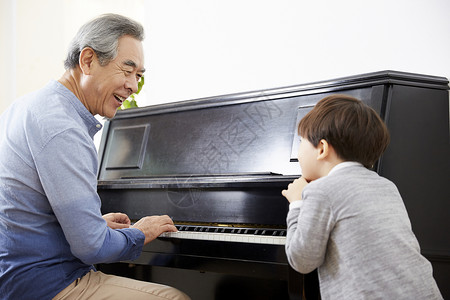 男孩看着祖父弹钢琴教育高清图片素材
