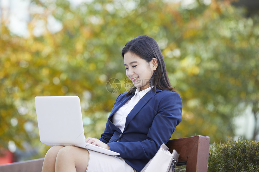 户外使用笔记本电脑处理工作的青年女性图片