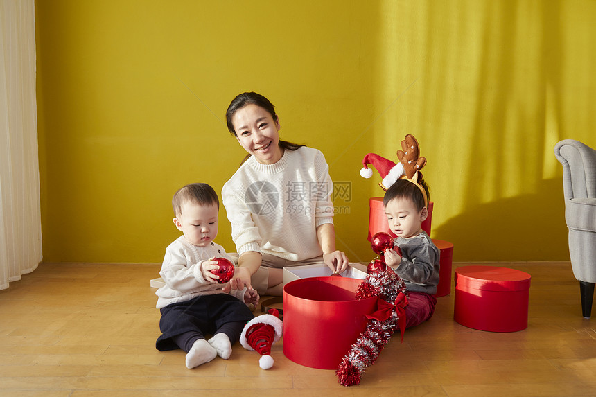 母亲照顾着两个婴儿打开圣诞礼物图片