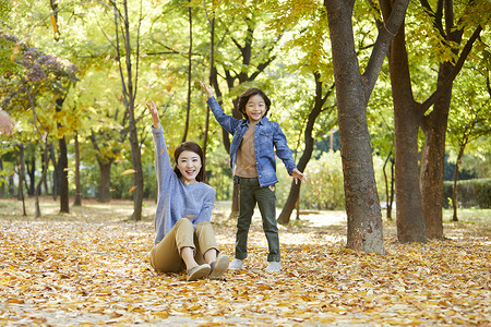 秋天妈妈陪孩子在公园里玩耍背景图片