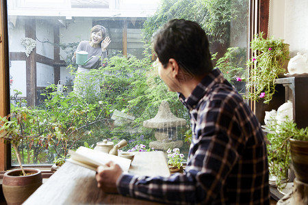 中年男子在茶馆看书和妻子打招呼花园高清图片素材