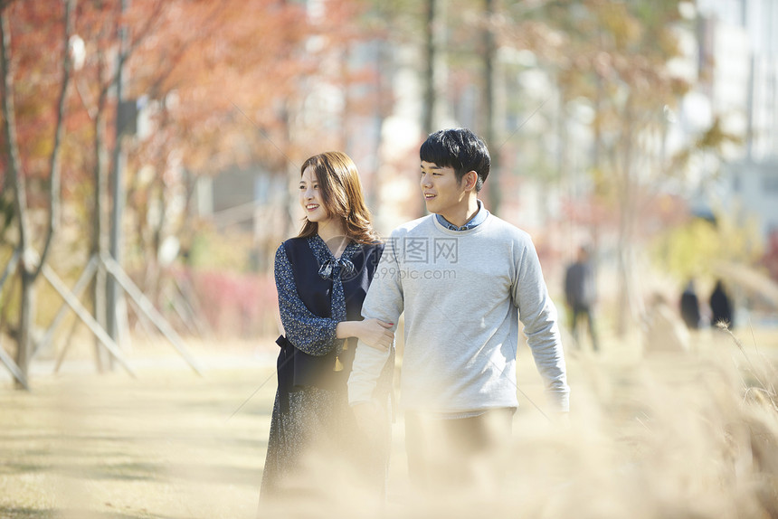 秋天公园里散步的年轻情侣图片