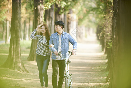 公园里郊游推着自行车的年轻情侣休息高清图片素材