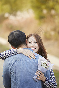 拥抱男朋友微笑的成年女子花束高清图片素材