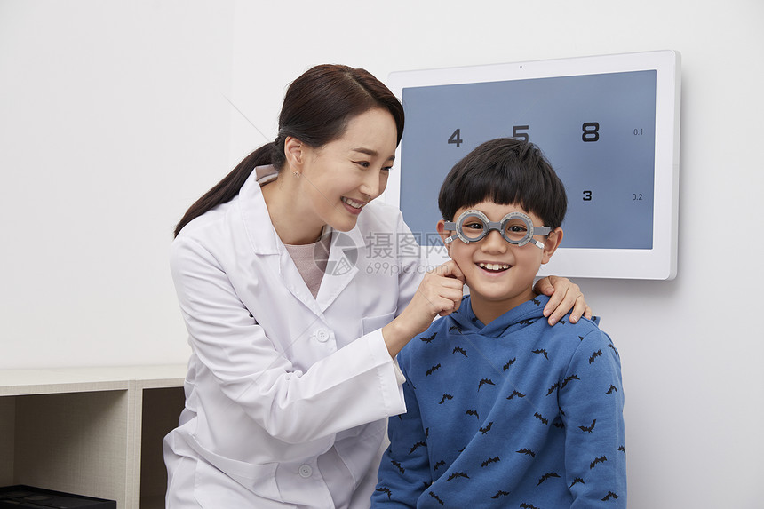 女医生为小男孩配戴近视眼镜
