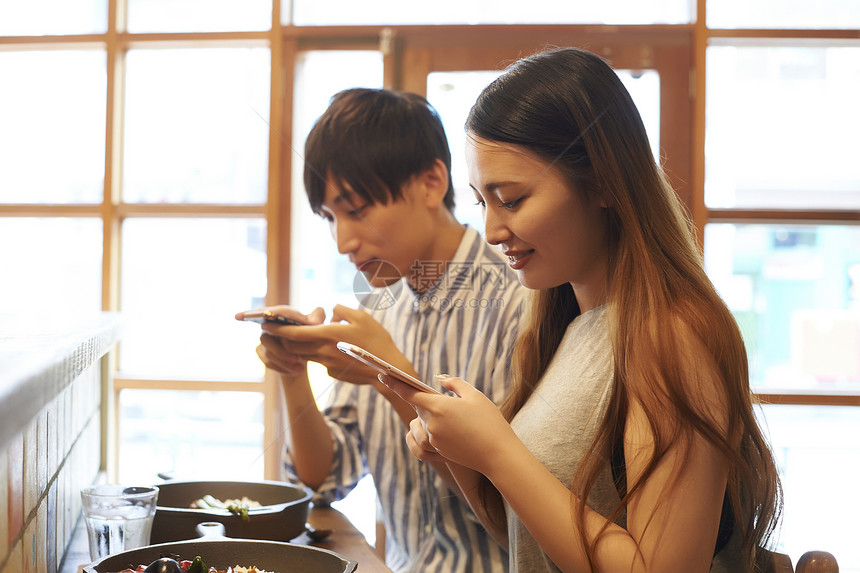 菜品痴迷年轻人采取与智能手机的夫妇食物图片