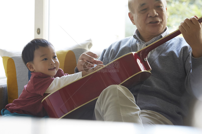 微笑的爷爷和孙子一起玩吉他图片