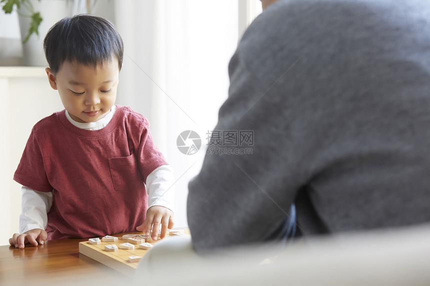 微笑的爷爷和孙子一起玩将棋图片