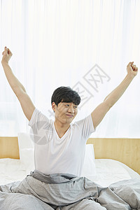 床上舒展双臂的成年男子图片