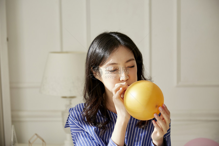 年轻女子在室内吹气球图片