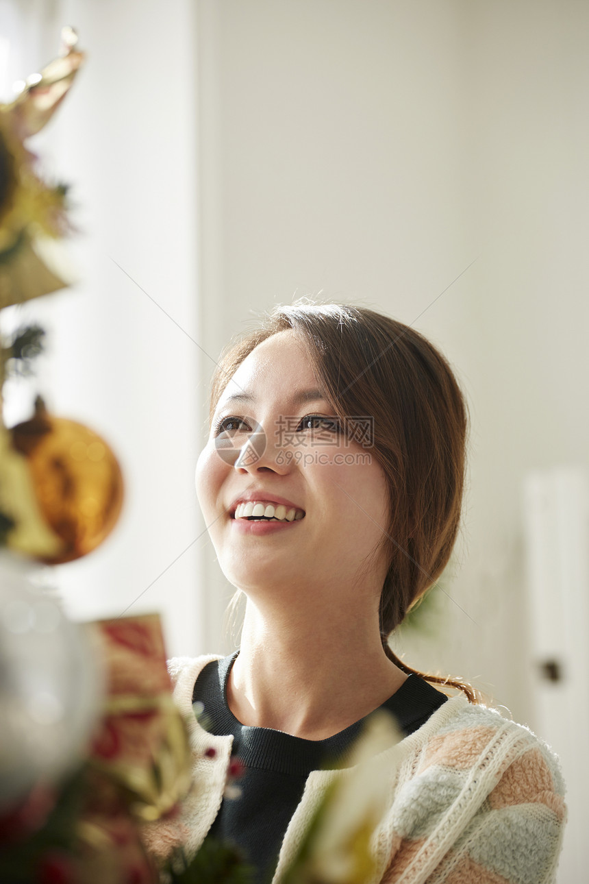 年轻女子在装饰圣诞树图片