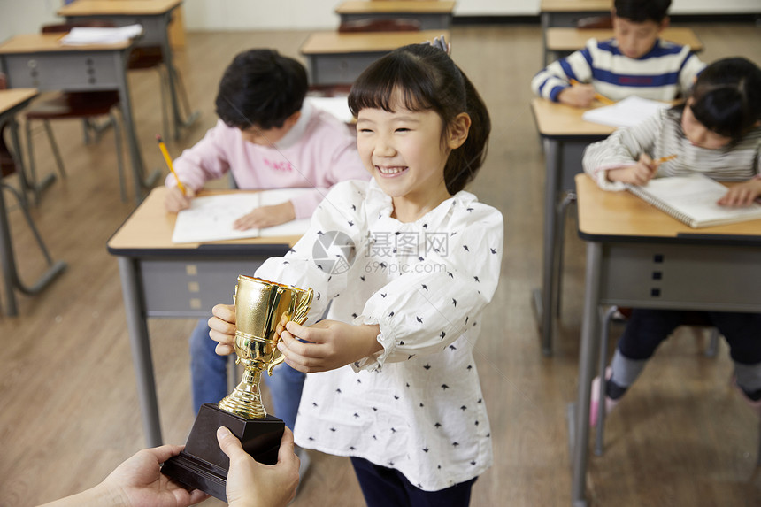 老师给小学生递奖杯图片