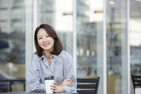户外咖啡馆喝咖啡微笑的年轻女子韩国人高清图片素材