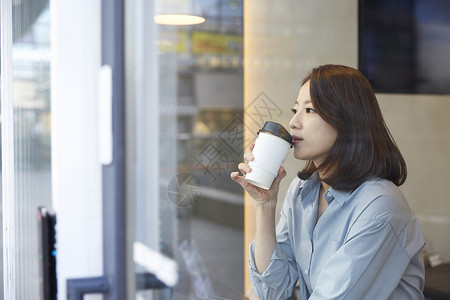 坐在窗边喝咖啡的青年女子安慰高清图片素材