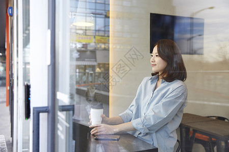 坐在咖啡馆窗边喝咖啡的女青年图片