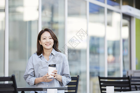 户外拿着咖啡杯的年轻女子新生代高清图片素材