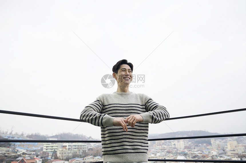 靠在栏杆上微笑的成年男子图片